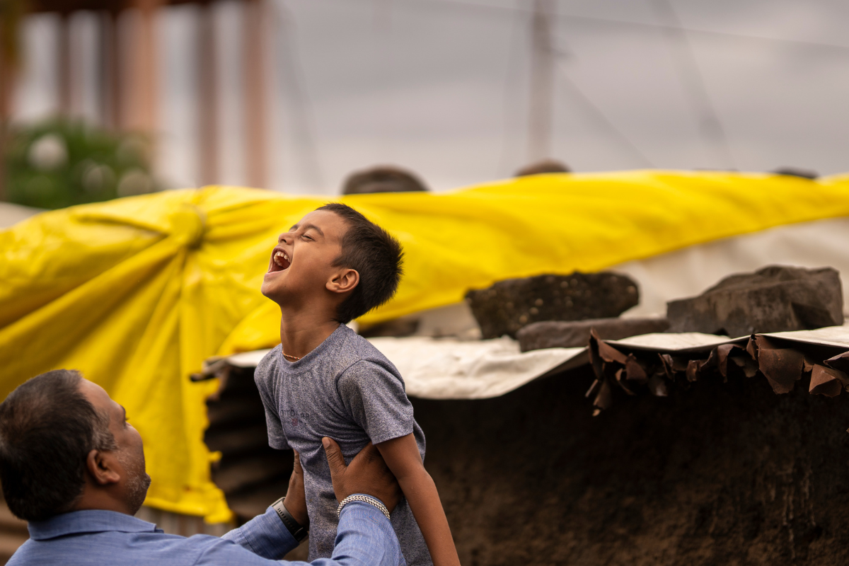 Young boy in rural India laughing with dad